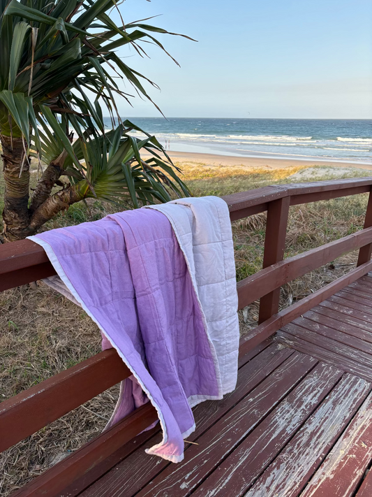 Pausa Quilted Throw draped over fence at the beach